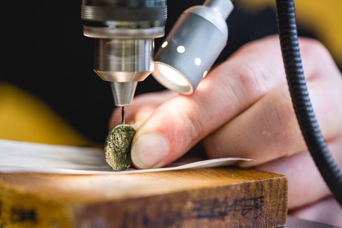 Coin is held and examined with a technical device.